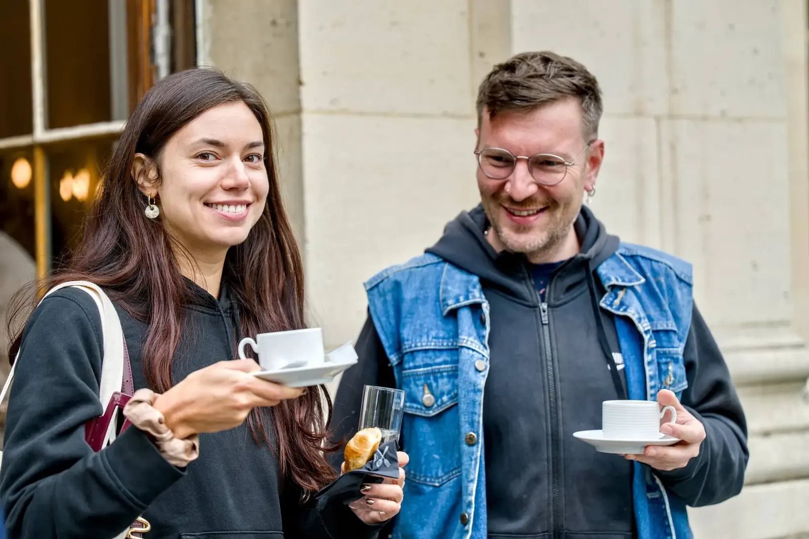 Two smiling participants, coffee cup in hand, in front of the château entrance