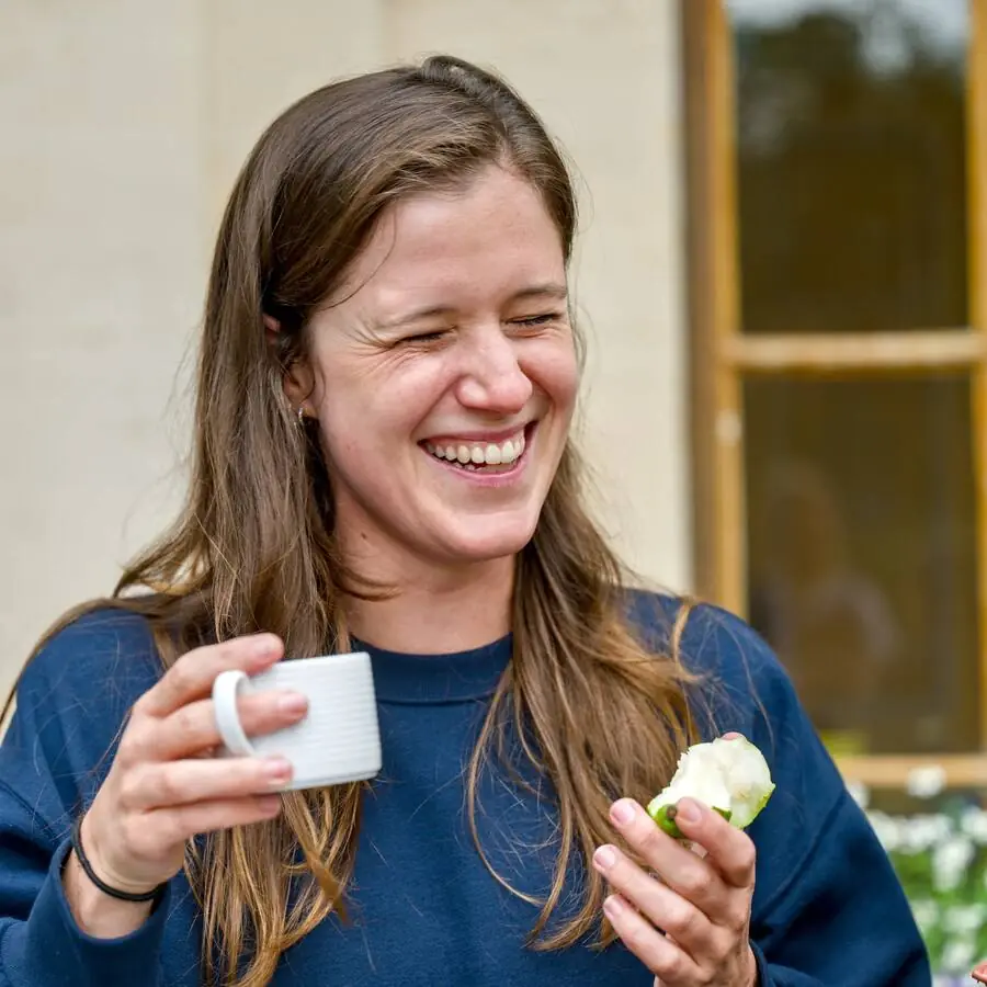 A participant laughs, holding a cup and a pastry