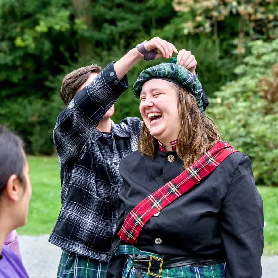 A participant bursts out laughing while adjusting a Scottish tam