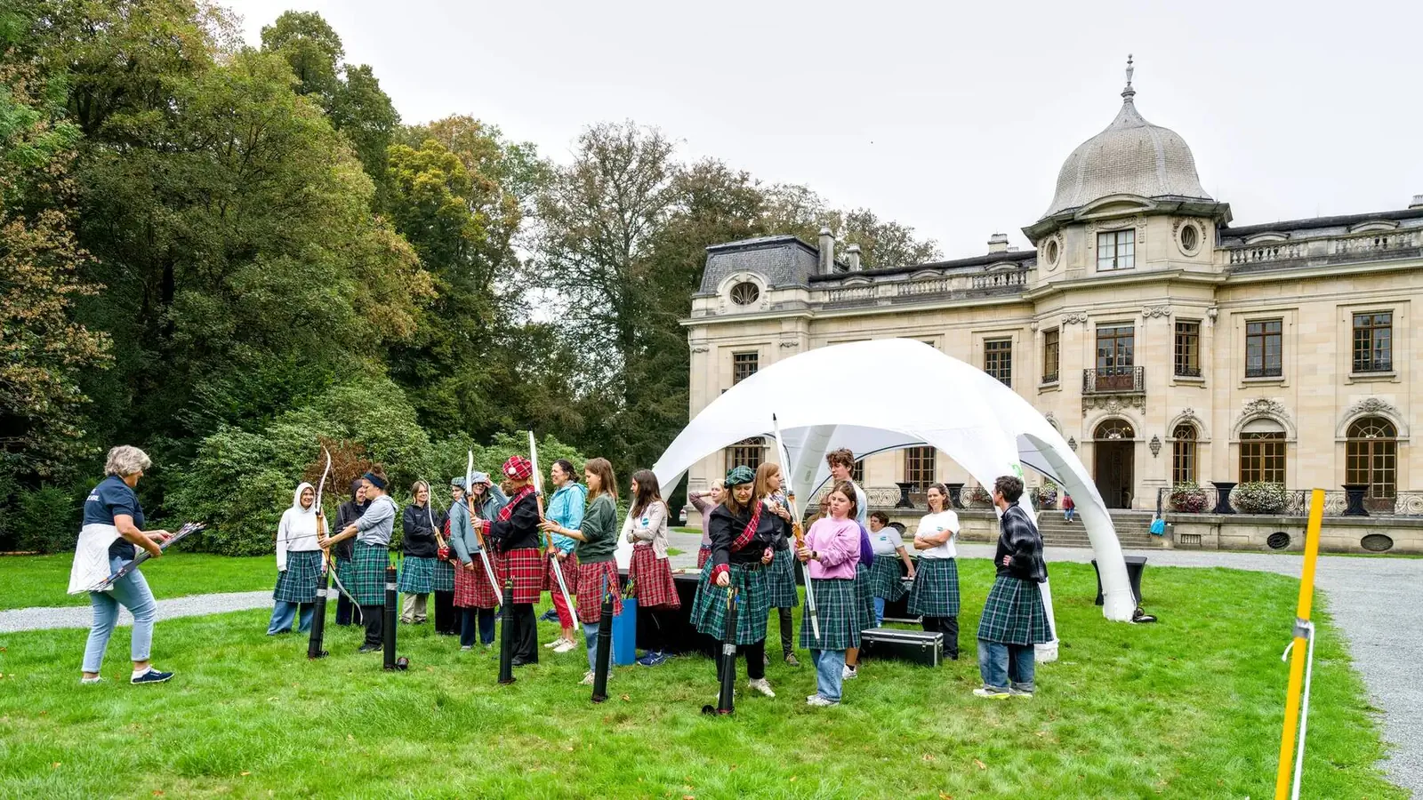 Team building under white marquees in the park, with the château in the background