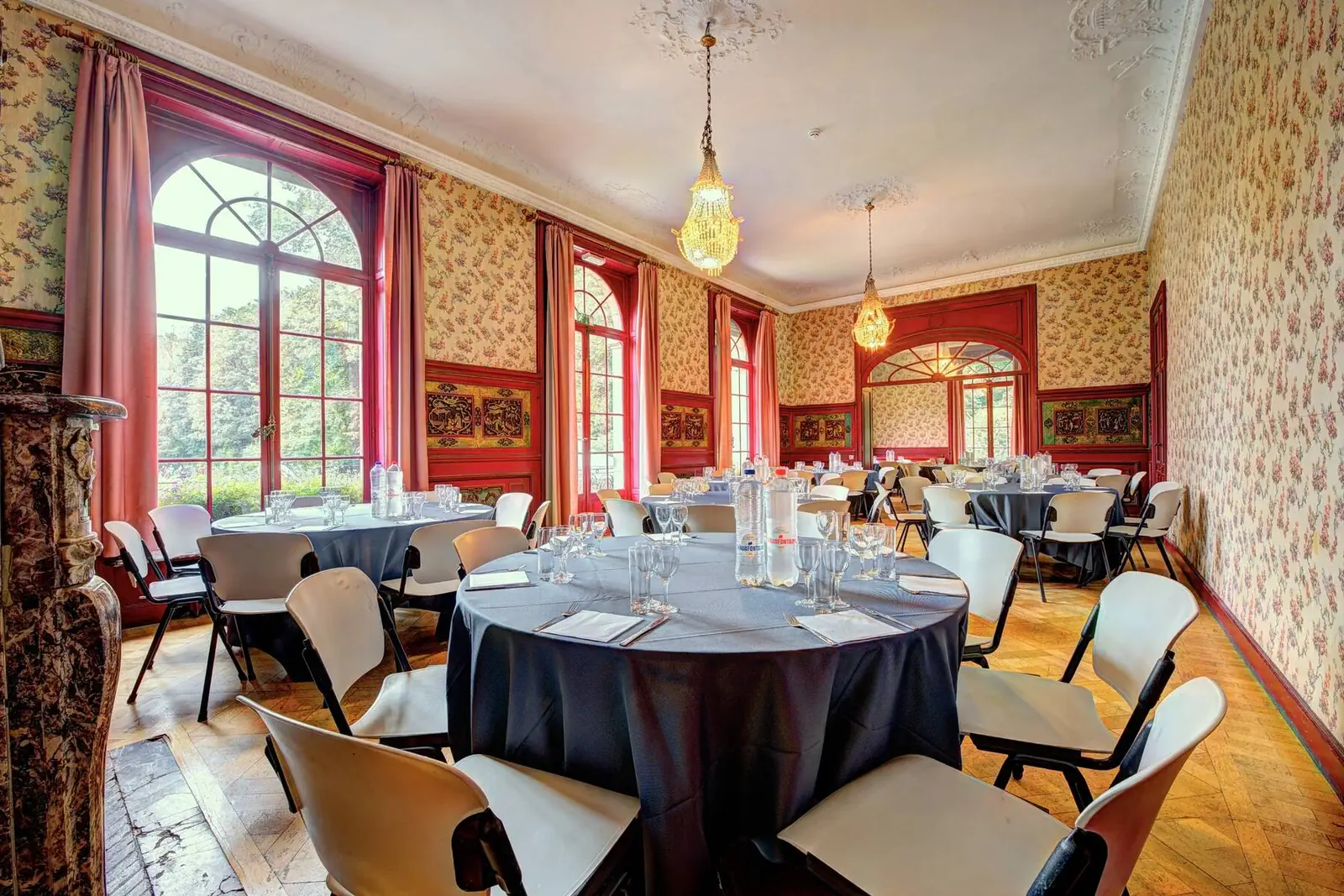 Red reception room set with round tables in blue tablecloths