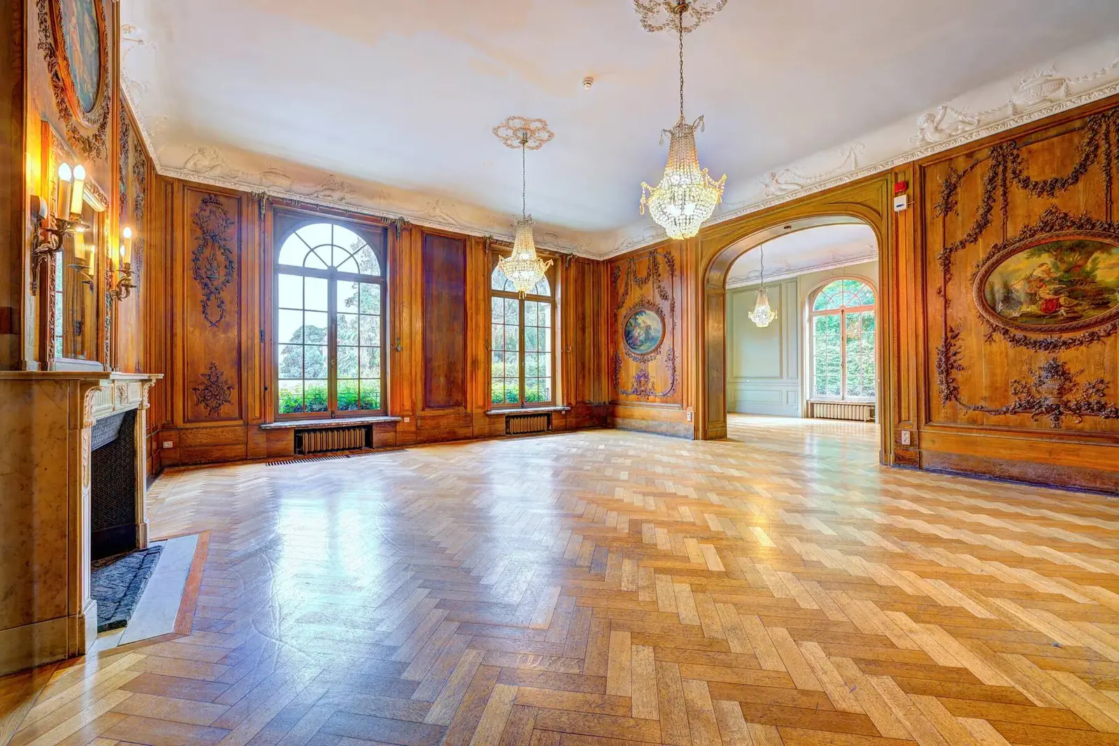 Salon with carved wood panelling, parquet flooring and fireplace