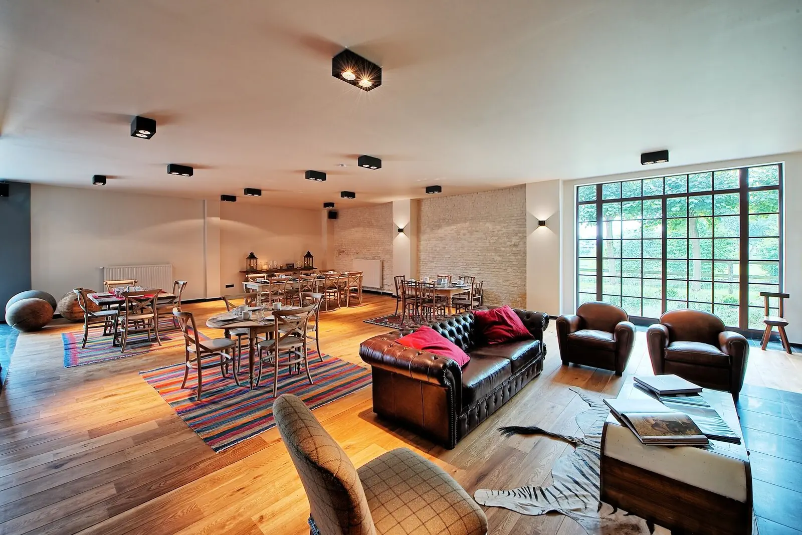 The Green Cottage living room: tables, Chesterfield sofa and large glass wall onto the garden
