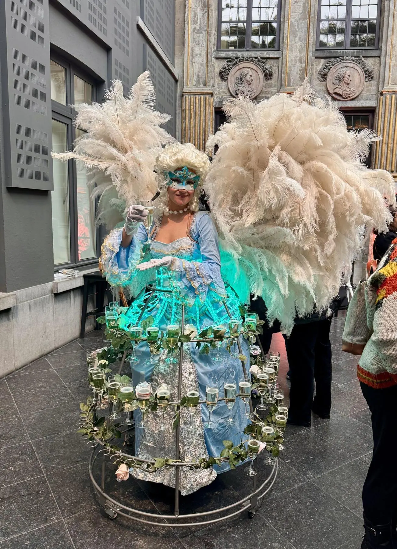 Performer in an illuminated feather costume during an evening event
